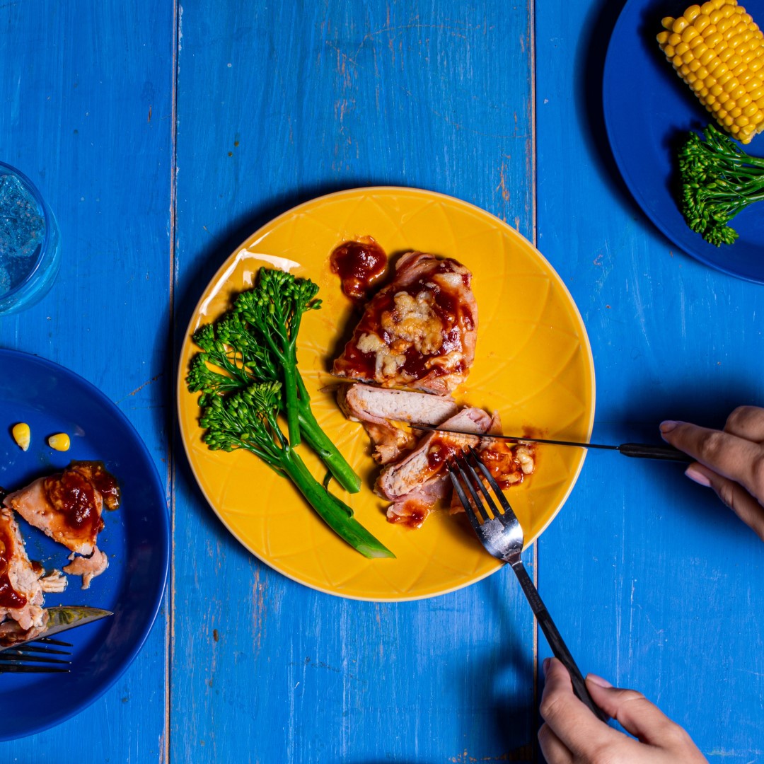 hunter style pork with brocolli on a yellow plate with blue backdrop